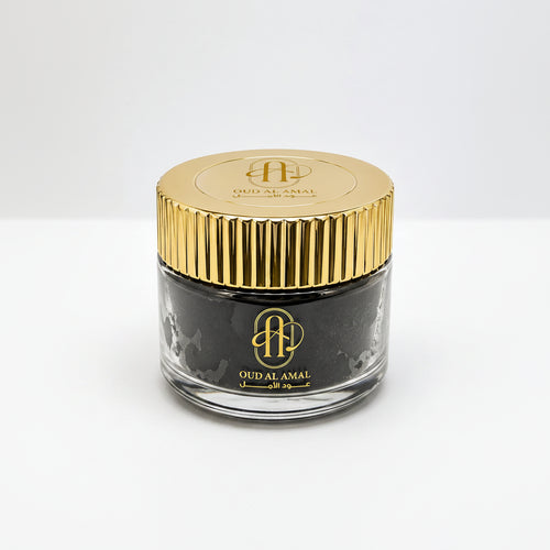 Jar of Oud Al Amal with gold lid on a white background
